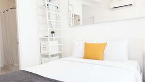 A white room with a bed, a white wardrobe, a mirror, and an air conditioning unit. - Aibonito Hotel 206 (Aibonito)