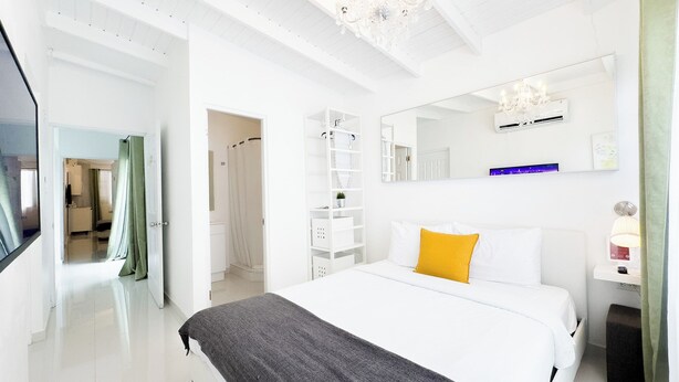 A modern hotel room with a large bed, a wardrobe, a mirror, and a chandelier. - Aibonito Hotel 206 (Aibonito)