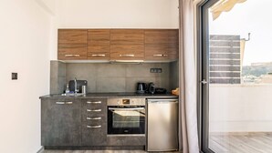 A compact kitchen with wooden cabinets, a built-in oven, and a refrigerator. - Dreamy Athens Penthouse with Acropolis View (Athina)