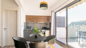 A modern kitchen with wooden cabinets and a dining area with a round table and chairs. - Dreamy Athens Penthouse with Acropolis View (Athina)