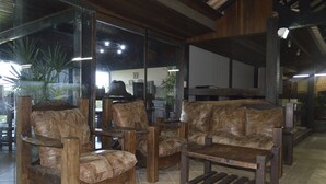 Quarto com mobiliário de madeira, incluindo sofá e cadeiras, e uma janela grande com vista para o exterior.