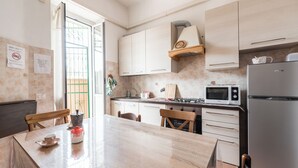 A kitchen with a wooden table, white cabinets, a microwave, and a refrigerator. - Large apartment with Wi-Fi and terrace (Roma)