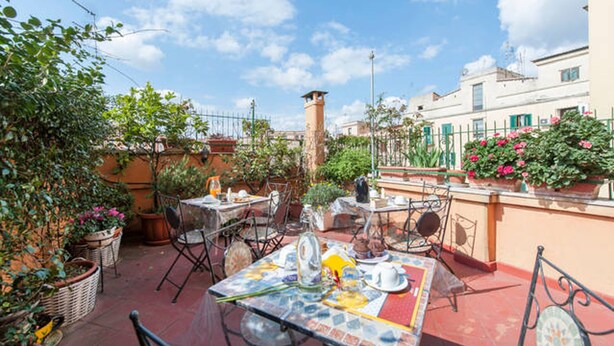 An outdoor patio with tables and chairs, surrounded by potted plants and a clear blue sky. - Large apartment with Wi-Fi and terrace (Roma)