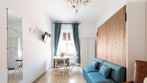 A modern living room with a blue sofa, a wooden accent wall, a dining area with a table and chairs, and a large mirror on the wall. - Large apartment with Wi-Fi and terrace (Roma)