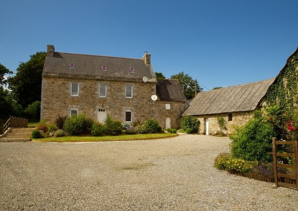 A stone building with a gravel driveway and a smaller adjacent structure.