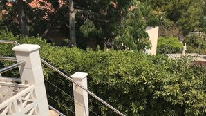 Eine Treppe mit Metallgeländer und beigefarbenen Stufen, umgeben von Grünpflanzen und einer weißen Wand.