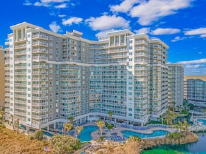 A multi-story hotel with balconies, a swimming pool, and a view of the surrounding area.