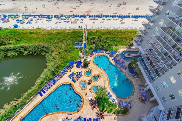 A resort with multiple swimming pools, a beach area, and a hotel building.