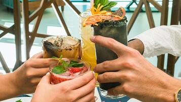 A table with drinks and a vase of flowers.