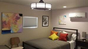 Ein Schlafzimmer mit einem Bett, einem Sessel, einem Nachttisch und Bildern an der Wand.