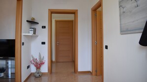 A hallway with a wooden door, a shelf with a small plant, and a wall-mounted light fixture. - Your home near Venice - Free Parking (Venezia)