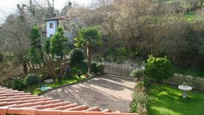 Un jardín con zona de patio, sendero de piedra y diversas plantas.