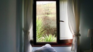 A bedroom with a single bed, a window with curtains, and a view of greenery outside. - Apartment 2 (Peñamellera Baja)