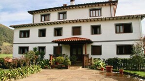 A two-story building with a tiled roof, multiple windows, and a covered entrance. - Apartment 2 (Peñamellera Baja)