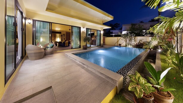 Una casa moderna con piscina, mobiliario exterior e iluminación en la entrada.