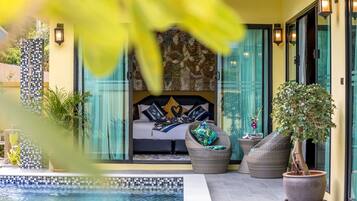 Ein Schlafzimmer mit einem großen Bett, Blick ins Freie und einem kleinen Balkon mit einem Blumentopf.