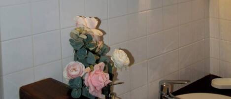 A bathroom with a sink, a mirror, and a wall-mounted light fixture.