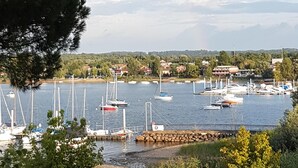 A marina with boats docked, a rainbow in the sky, and a view of a town in the background. - EVASION AU FIL DE L'EAU.... (CIN IT003062C24G5JPZGD) (DORMELLETTO)
