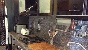 A kitchen with a gas stove, toaster, and a cutting board on the counter. - EVASION AU FIL DE L'EAU.... (CIN IT003062C24G5JPZGD) (DORMELLETTO)