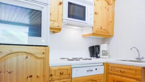 Una cocina con armarios de madera, microondas, cafetera y lavavajillas.