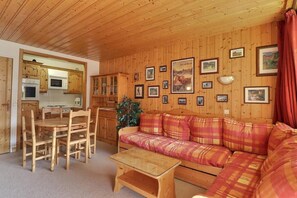 A wooden interior with a dining area, sofa, and kitchen.