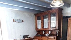 A dining area with a wooden table and chairs, a fish decoration on the wall, and a cabinet with glass doors.