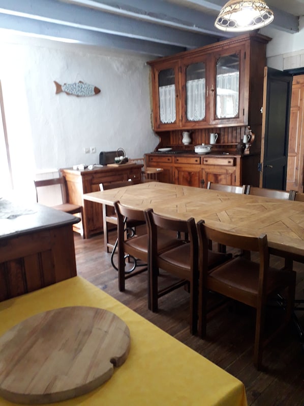 A dining area with a wooden table and chairs, a fish decoration on the wall, and a cabinet with glass doors.