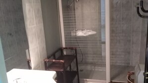 A bathroom with a shower, a sink, and a wooden floor.