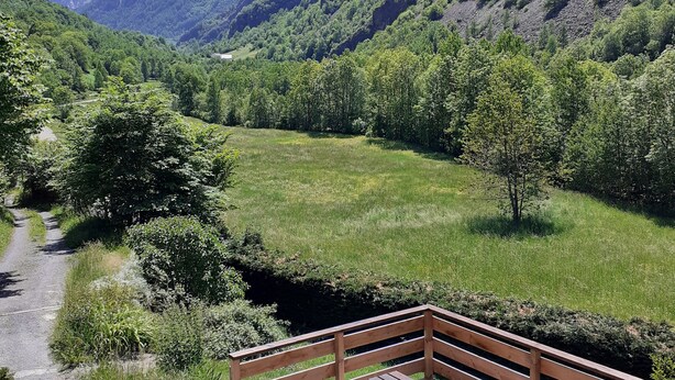 A wooden bench overlooking a lush valley with a clear sky.