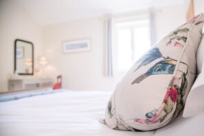 Une chambre à coucher avec un lit, une table de chevet, un miroir et une fenêtre.