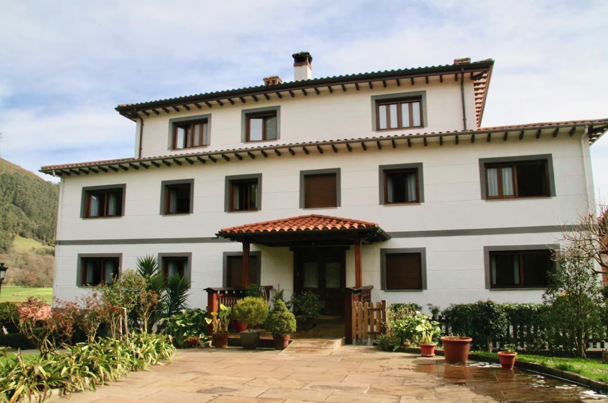 A two-story building with a tiled roof, multiple windows, and a covered entrance.