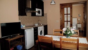 Cuina compacta amb microones, rentatallges i rentadora. Hi ha una taula de dinar amb cadires i un vas de flors.