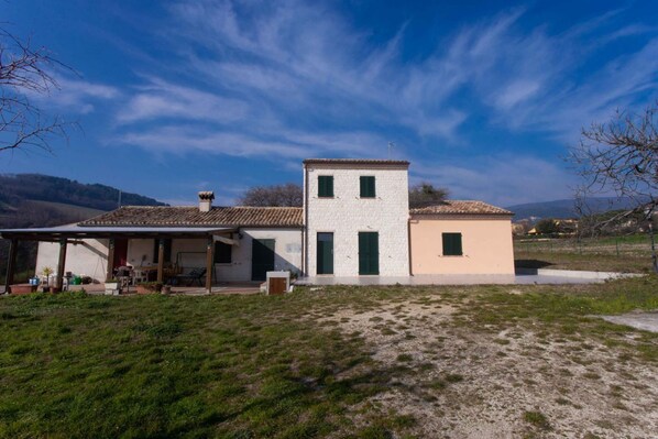 Une maison à deux étages dotée d’un patio couvert, d’une petite tour et d’un garage séparé.