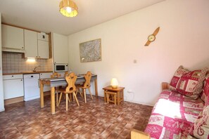 Um espaço compacto para viver, com cozinha, área de refeições e sofá.