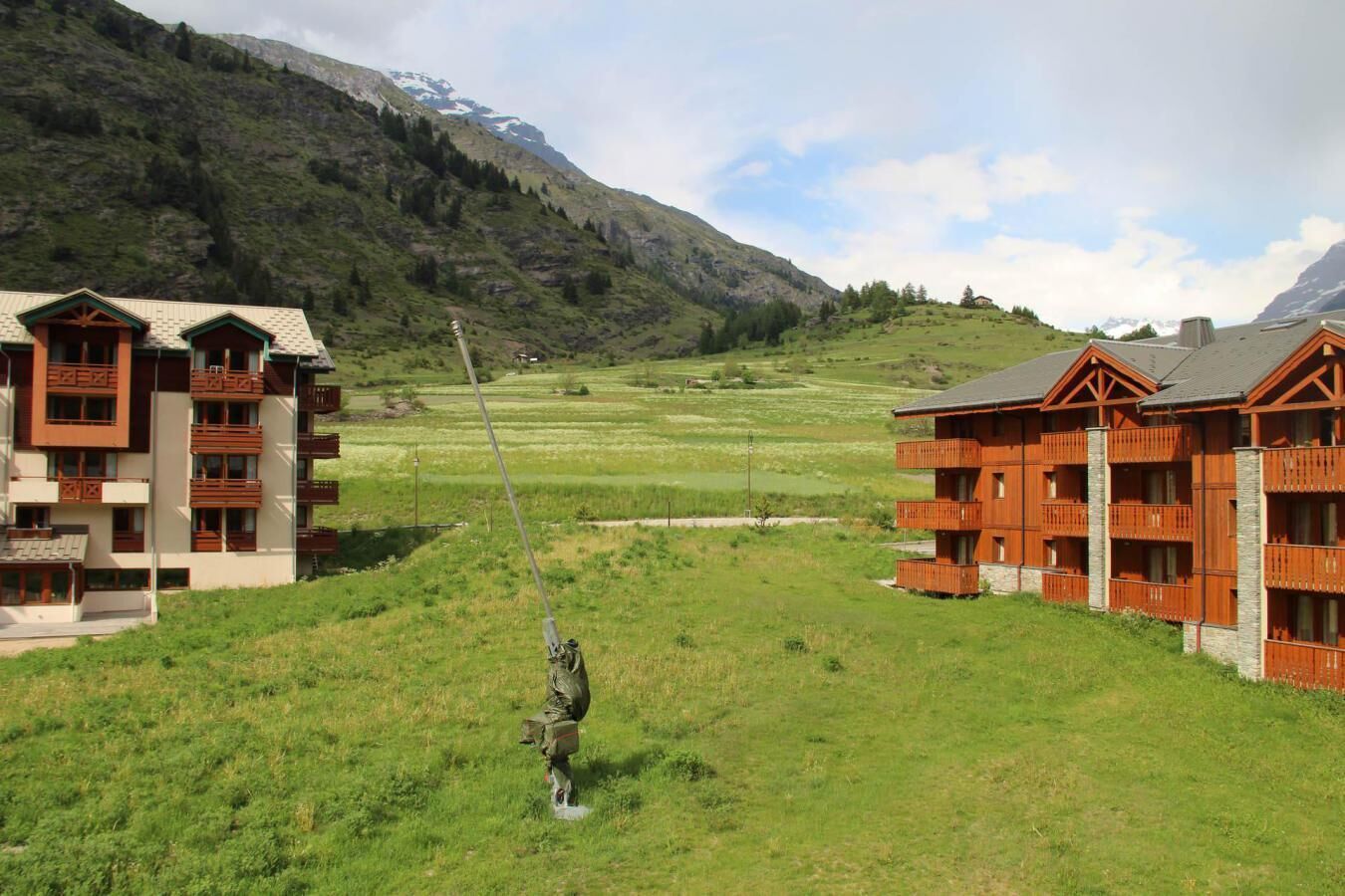 A hotel with multiple floors, balconies, and a mountainous backdrop.