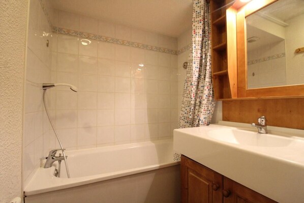 A bathroom with a bathtub, a sink, and a mirror.