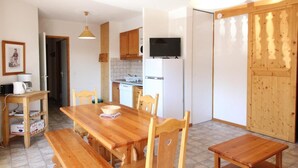 A compact kitchen with wooden cabinets, a built-in microwave, and a television above the counter. - 1st floor, balcony, tv, ski locker, 46m², Aussois (Aussois)