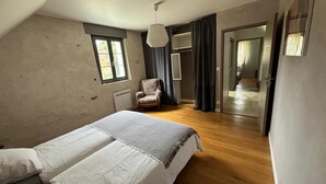 A bedroom with a bed, a chair, a window, and a door leading to another room. - Typical barn from the 17th century, 120 square meters of living space (La Membrolle-sur-Choisille)