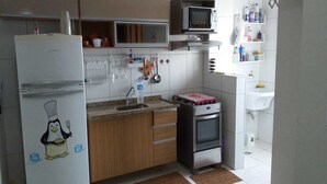 Eine kleine Küche mit Kühlschrank, Mikrowelle, Backofen und Spüle.
