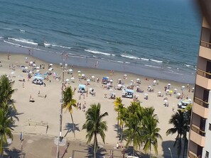 Una playa con palmeras, sombrillas y gente.