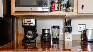 Une cuisine équipée d’une machine à café, d’un mixeur et d’un four à micro-ondes. On y trouve des couteaux et un grille-pain sur le plan de travail.
