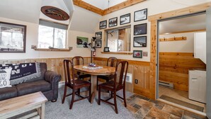 Un intérieur de chalet chaleureux avec un coin repas, des murs en bois et une cheminée.