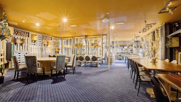 A spacious dining area with multiple tables and chairs, a patterned carpet, and a warm ceiling design. - Archibald Hotel (Kurrajong Heights)