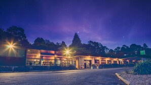 A modern building with large windows, a parking lot, and a sign indicating a business. - Archibald Hotel (Kurrajong Heights)