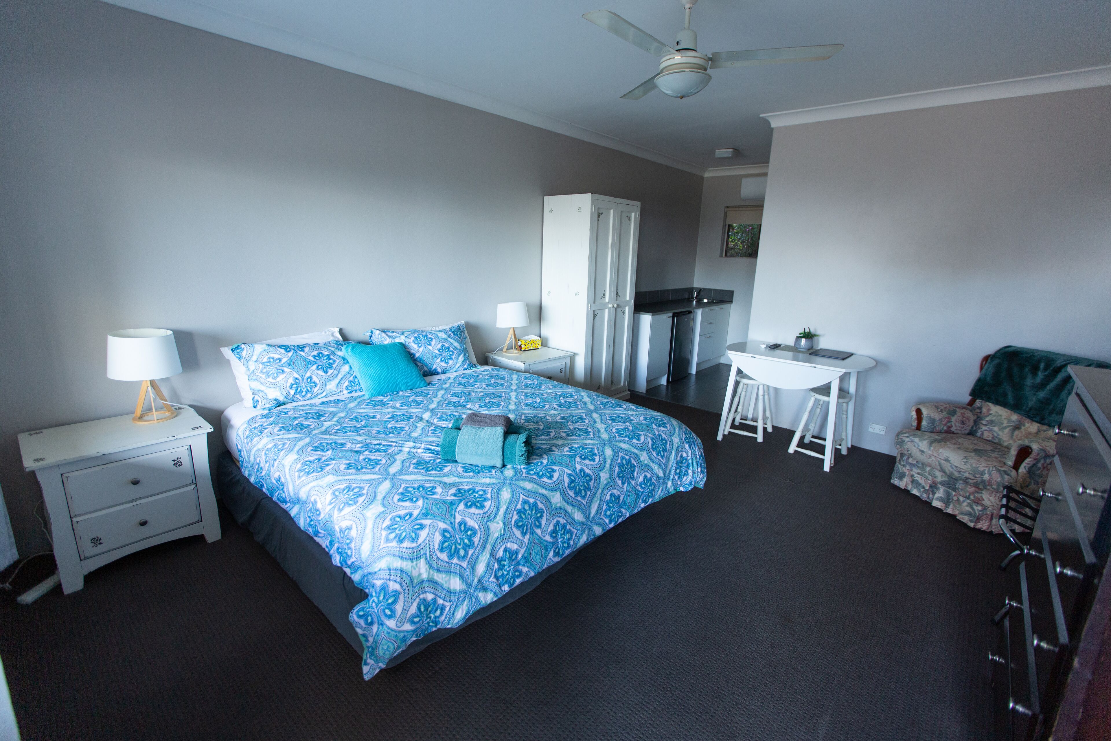 A bedroom with a bed, nightstands, a desk, a chair, and a wardrobe.