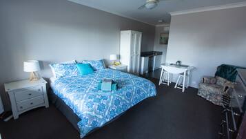 A bedroom with a bed, nightstands, a desk, a chair, and a wardrobe.