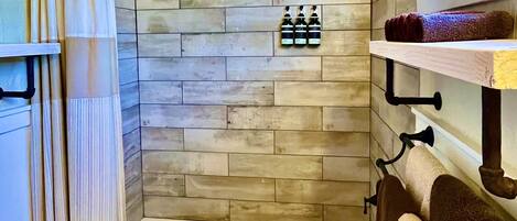 A bathroom with a wooden ceiling, a bathtub, a toilet, and a shower curtain.