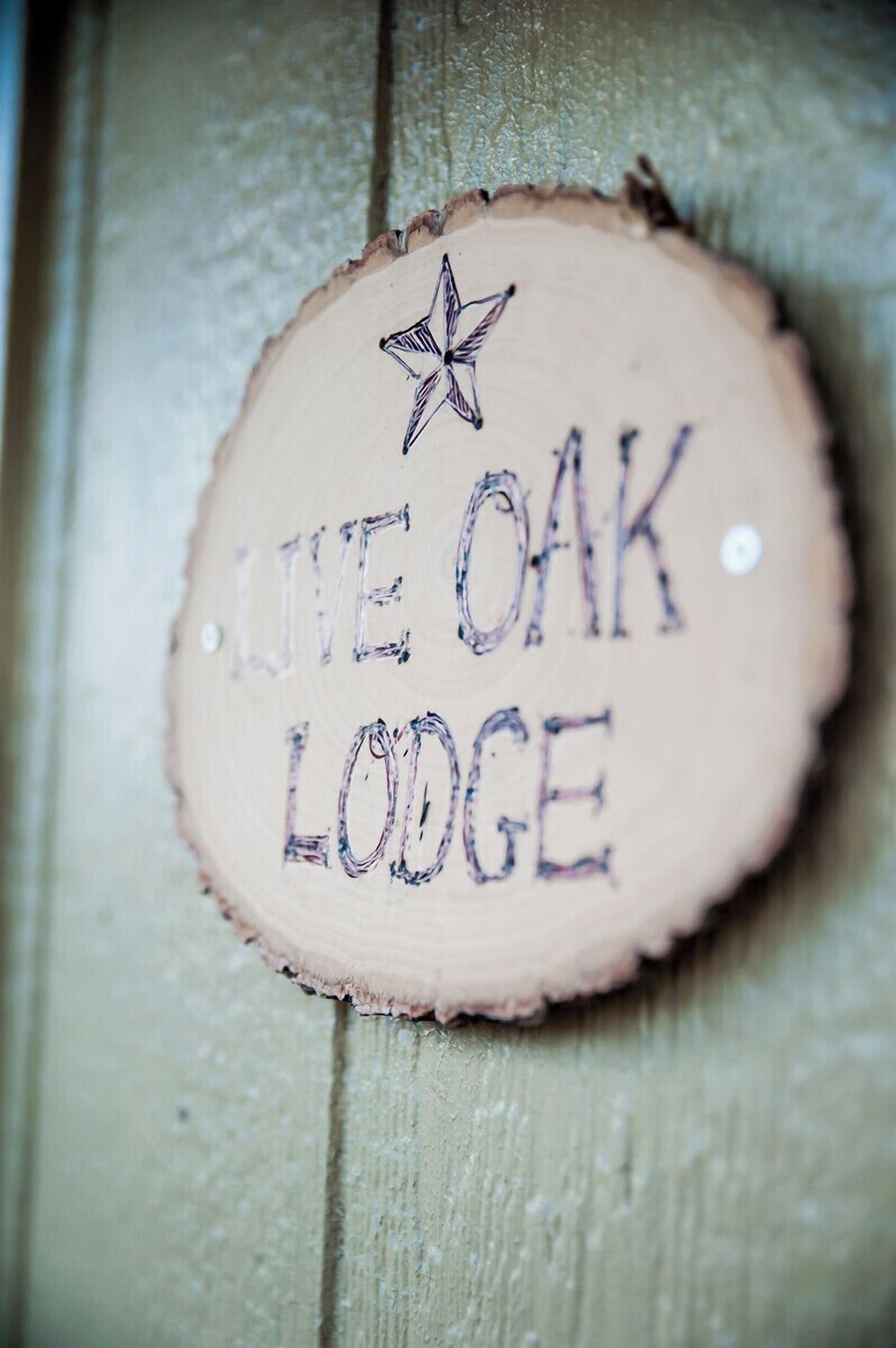 A wooden sign with the text "LIVE OAK LODGE" and a star symbol.