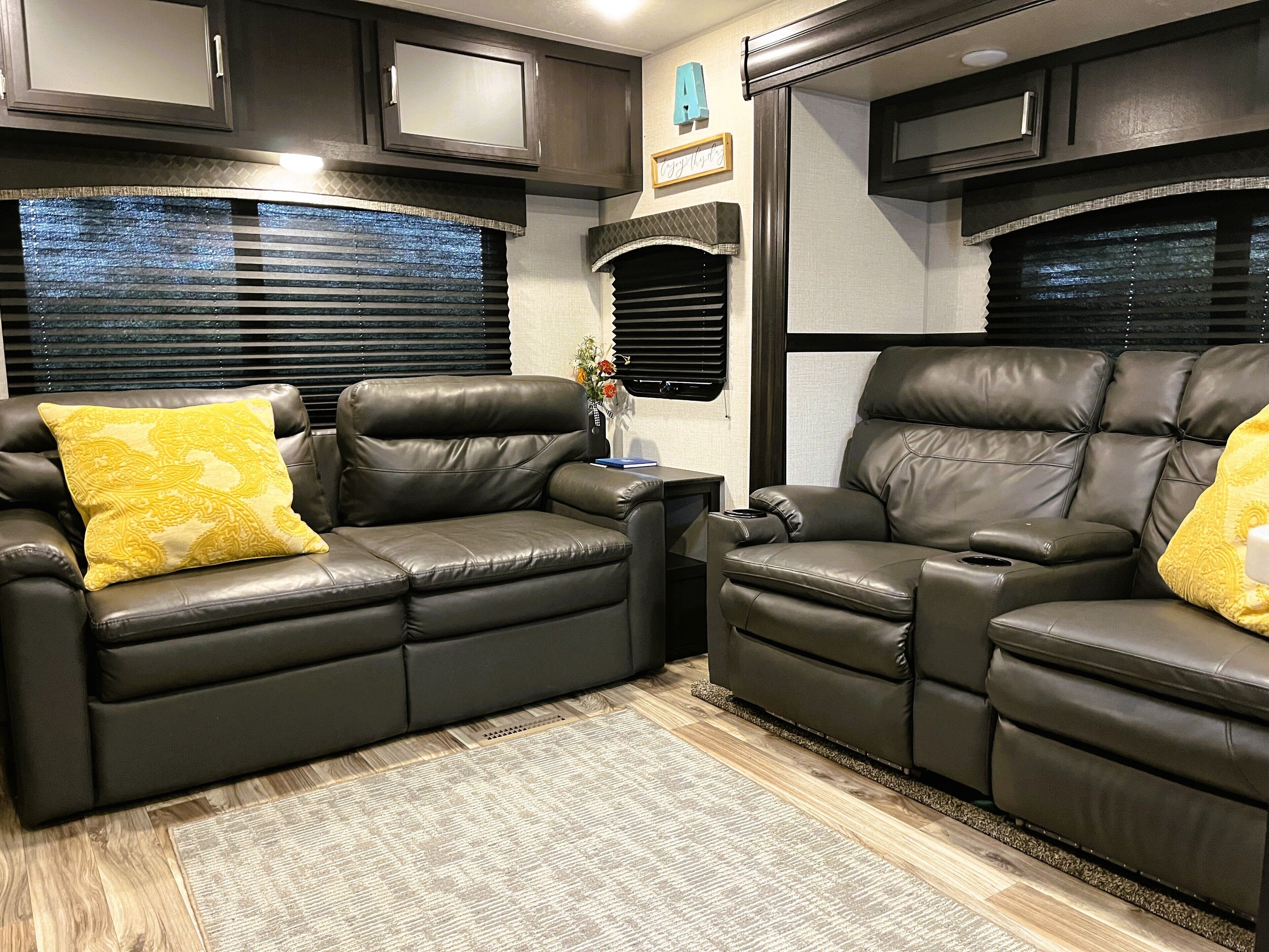 A cozy RV interior with two leather recliner sofas, a small side table, and a decorative vase.