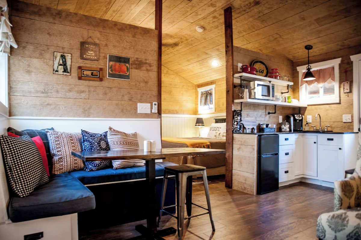 Ett mysigt vardagsrum med en soffa, ett matbord och ett köksutrymme med mikrovågsugn och skåp.